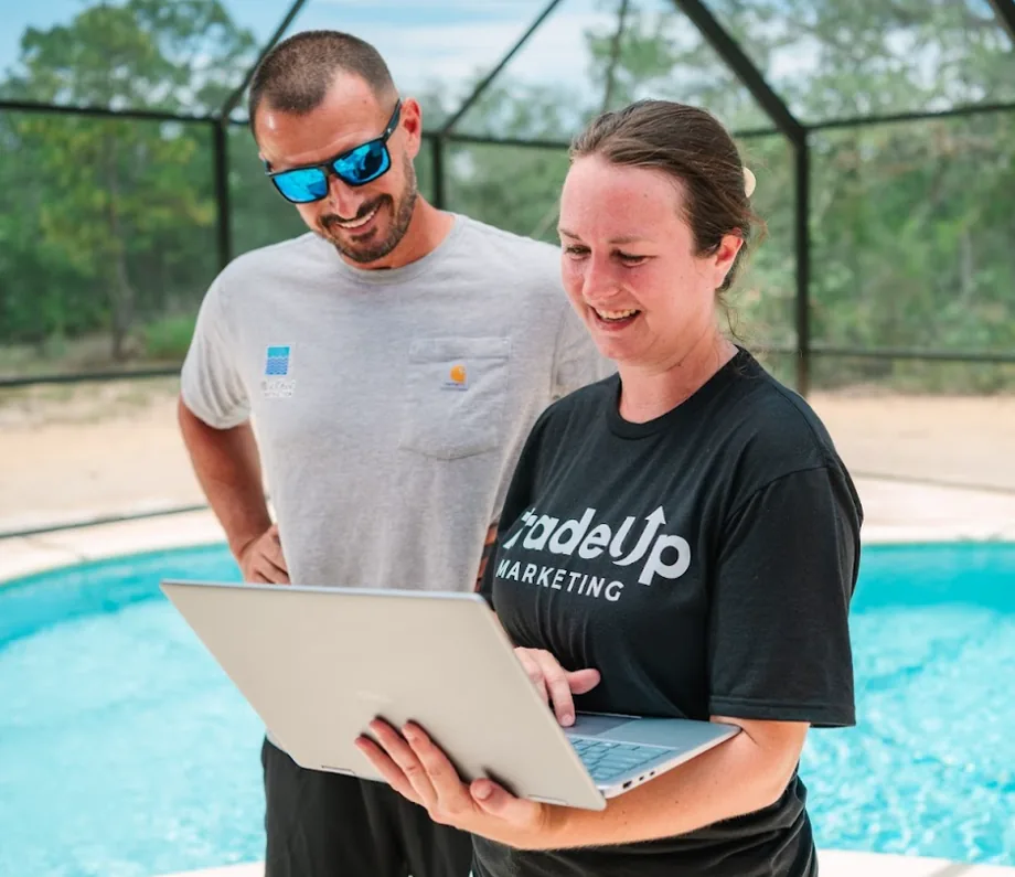 TradeUp Marketing team member showing a pool contractor his new website on a laptop beside a screened pool