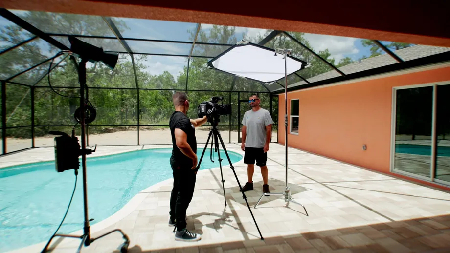 TradeUp Marketing crew setting up lights and a camera for a poolside shoot at a client home