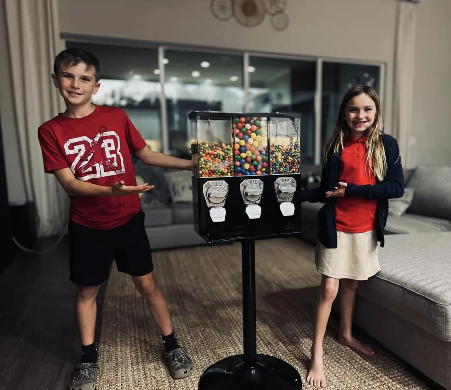 Two children presenting a gumball machine during a product photo shoot