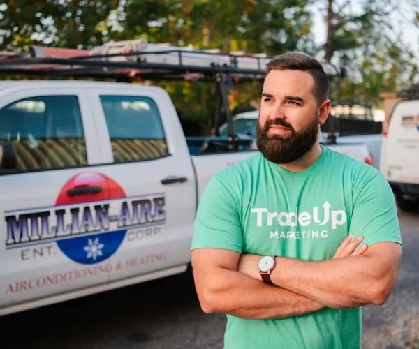 Jordan Lung in a TradeUp Marketing shirt in front of a Millian-Aire air conditioning and heating truck