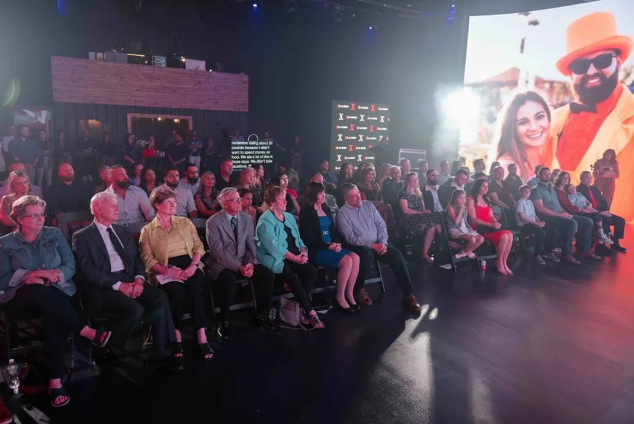 Live event audience seated in front of large stage screens
