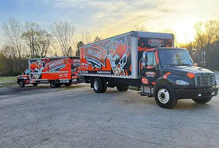 Immediate Movers project photo — two branded Immediate Movers trucks parked on the lot at sunset