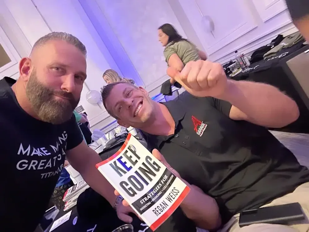 Regan Weiss holding a copy of his book Keep Going with a reader